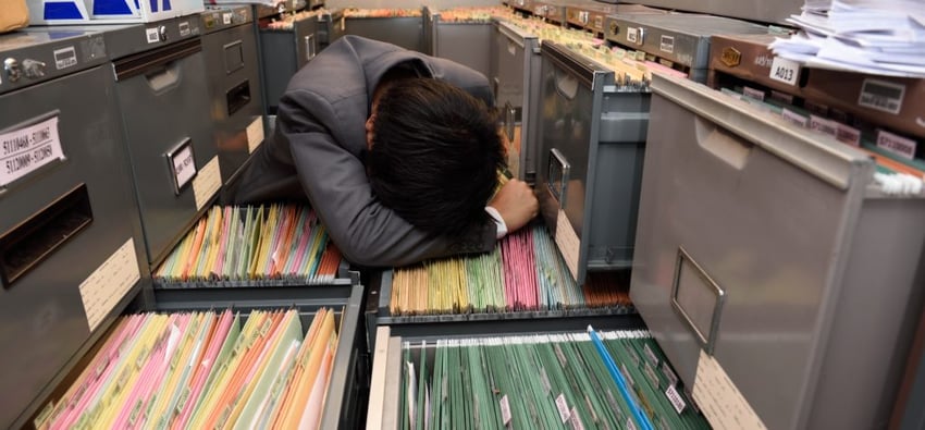 office worker burdened by file cabinets